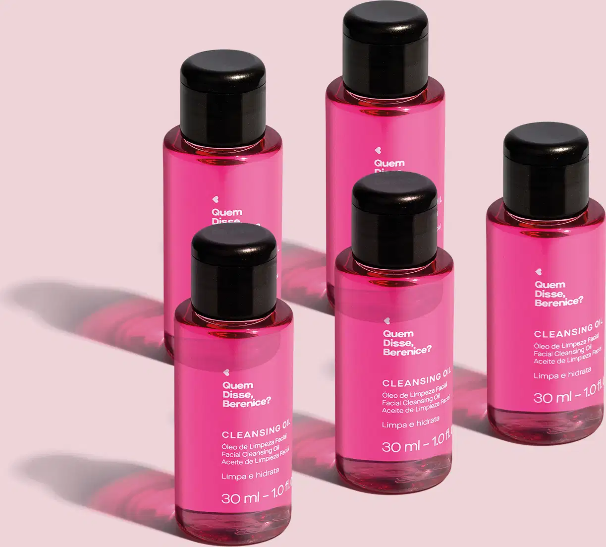 Cinco frascos de óleo de limpeza facial Cleansing Oil Quem Disse, Berenice? em frasco transparente com líquido rosa e tampa preta em fundo lilás.