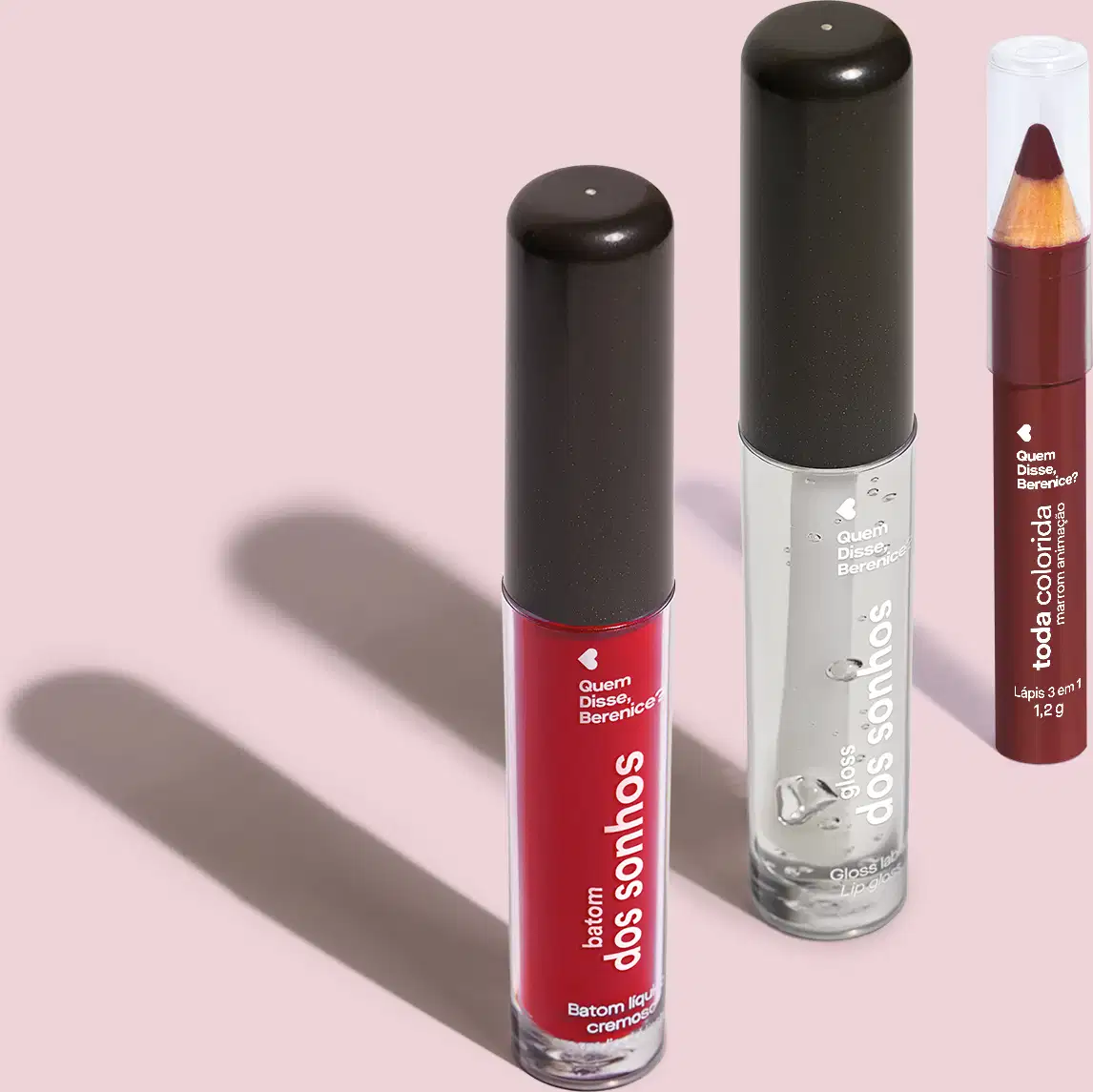Frasco transparente com líquido vermelho de Batom dos Sonhos, frasco transparente com líquido claro e tampa preta de gloss labial incolor Batom dos Sonhos e lápis 3 em 1 Toda Colorida Marrom Animação, todos da marca Quem Disse, Berenice? em fundo lilás.