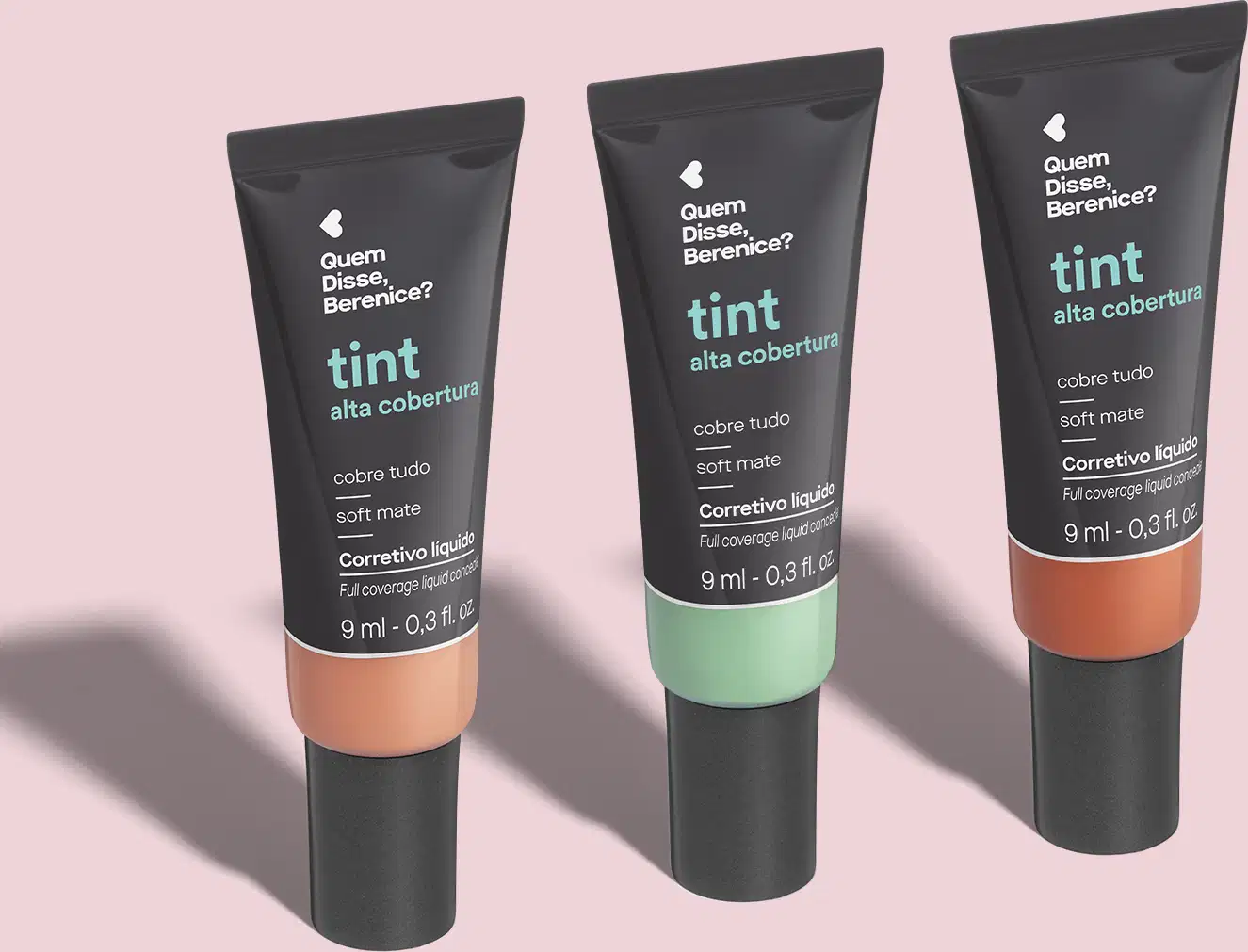 São três tubos de maquiagem corretiva líquida da marca Tint, com alta cobertura e acabamento mate. Os tubos plásticos pretos têm a parte inferior colorida em tons salmão, verde e laranja.