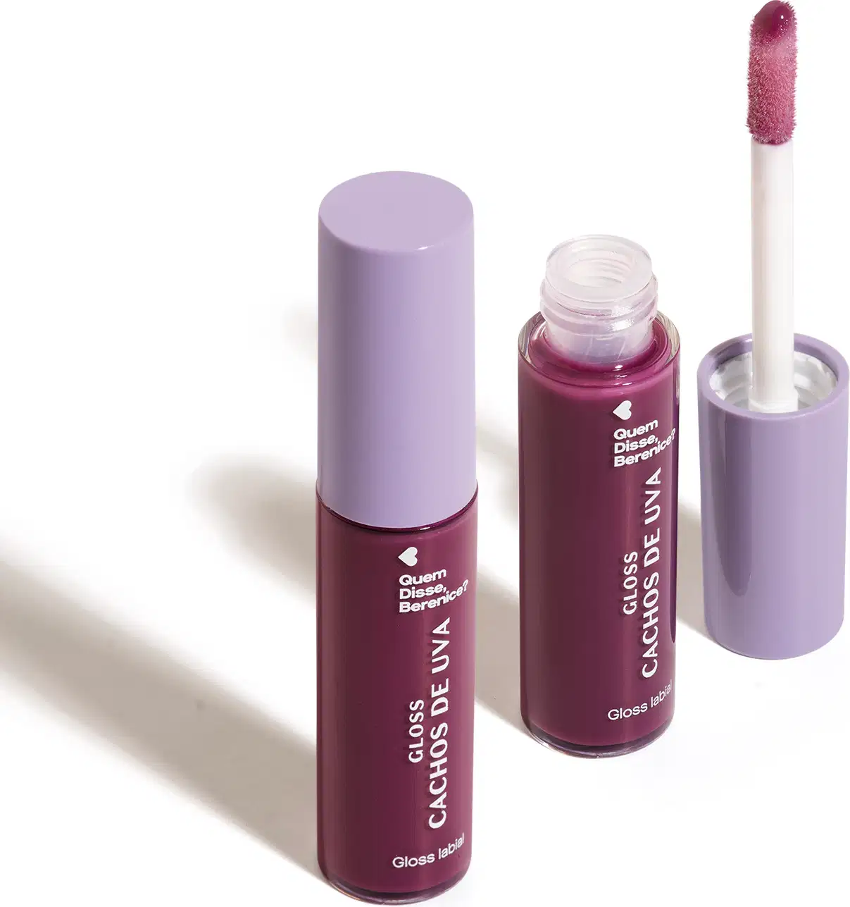 Imagem de combo com dois frascos de 10ml contendo gloss labial Cachos de Uva QDB E Cuide-se Bem Quem Disse, Berenice?. A embalagem é transparente com conteúdo roxo, tampa cinza e aplicador macio na cor roxa. O fundo é branco com leve sombreado.
