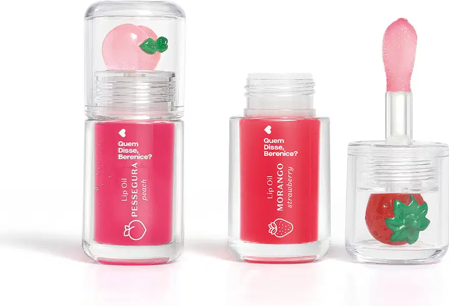 Imagem do Combo Lip Oil Quem Disse, Berenice? com um produto na cor Vermelho Morango em tonalidade vermelha e morango decorativo e Rosa Fúcsia Pessegura em tonalidade rosa claro e pêssego decorativo. As embalagens são transparentes com aplicador. macio.