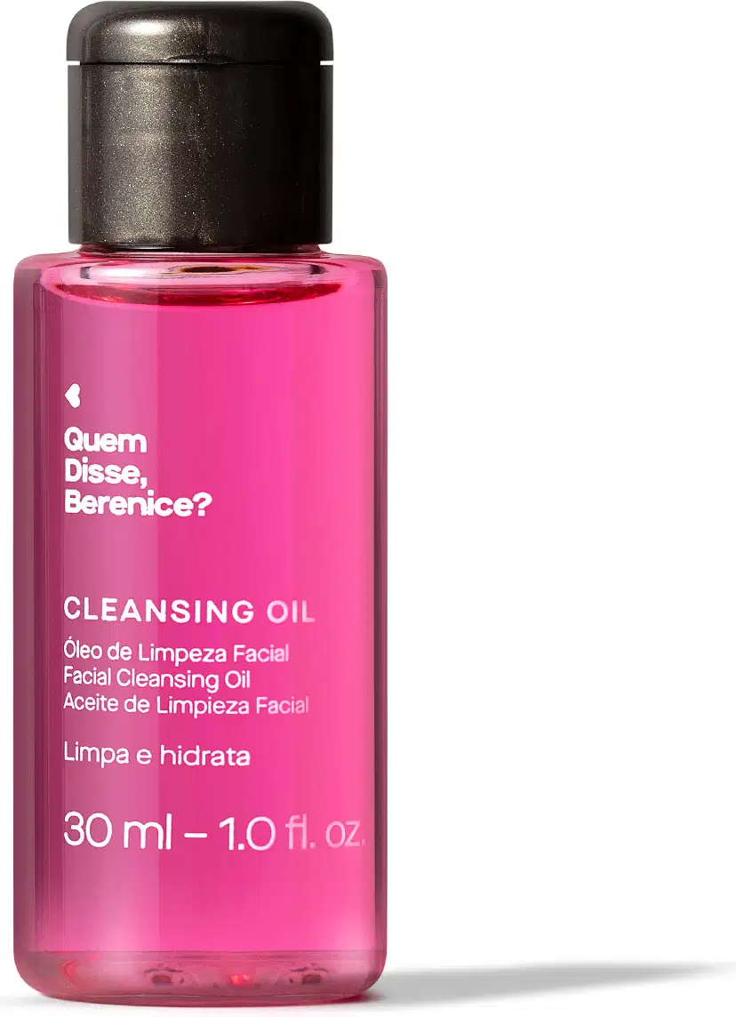 Imagem de frasco transparente e tampa preta contendo um líquido rosa com rótulo branco e texto "Quem disse, Berenice? Cleansing Oil" em letras pretas, trazendo 30 ml de óleo de limpeza facial. Está em fundo branco e há um leve sombreado na superfície.