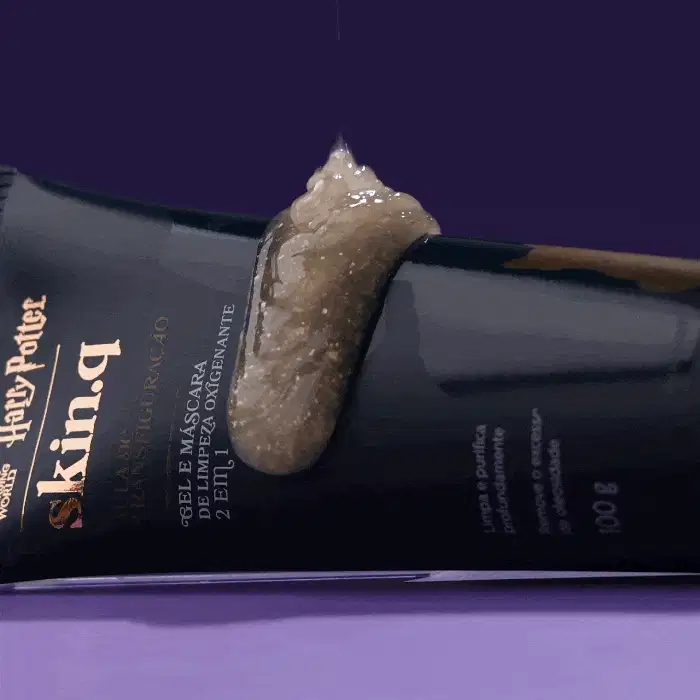 Bisnaga azul-marinho com letras na cor dourada e branca de gel e máscara de limpeza Borbulhante 2 em1 Skin q. Quem Disse Berenice? Harry Potter em fundo verde escuro e superfície azul com líquido brilhante caindo sobre a embalagem.