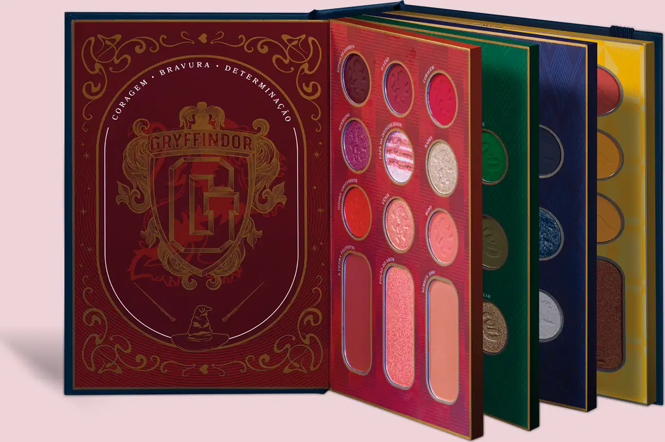 Paleta de maquiagem. Dentro, há quatro paletas individuais nas cores vermelho, verde, azul e amarelo. Cada paleta contém vários compartimentos redondos com diferentes tonalidades de sombras prensadas. O conjunto apresenta design inspirado em Harry Potter.