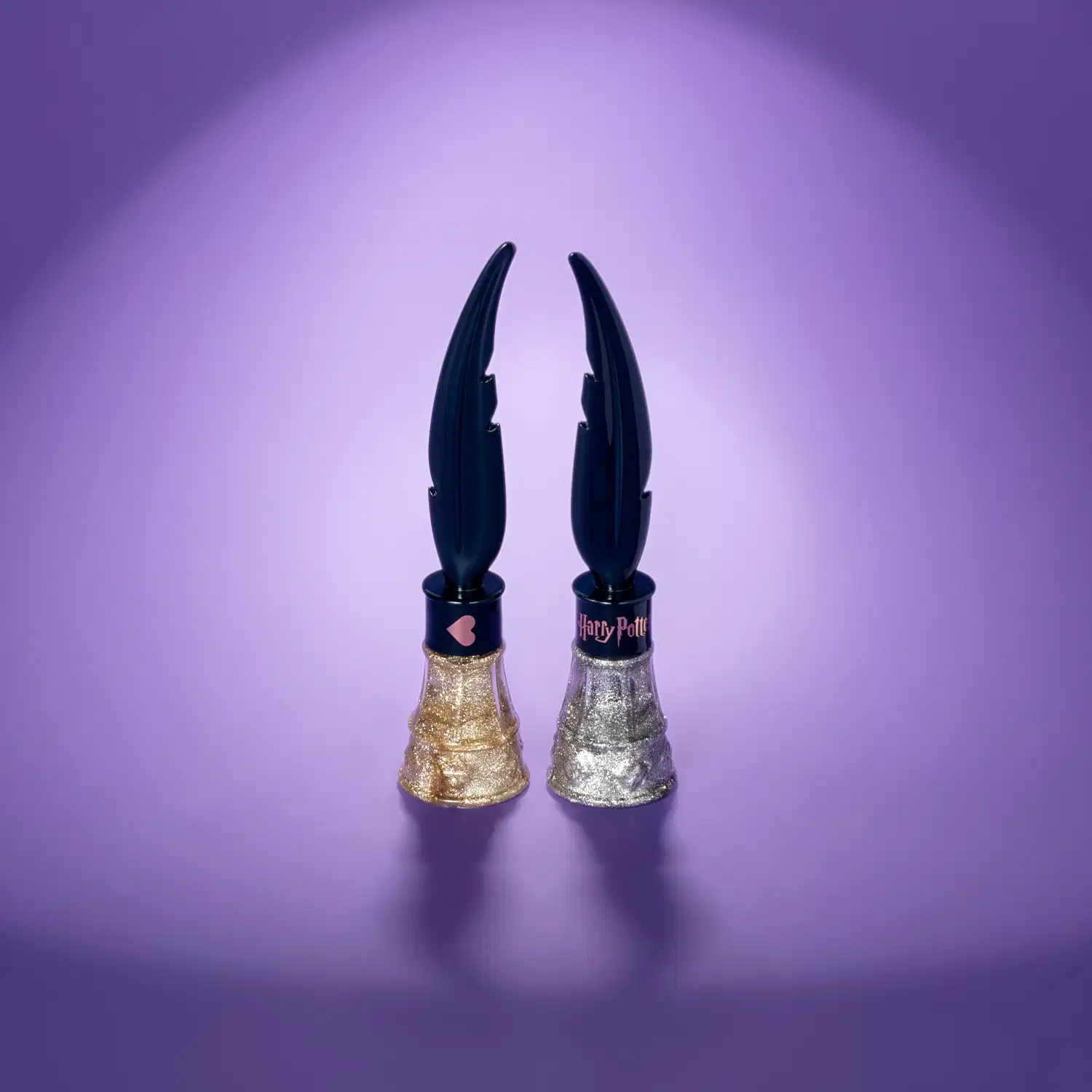 Dois vidros triangulares nas cores dourada e prateada com tampas pretas em formato de pena em fundo azul com iluminação em volta dos produtos.