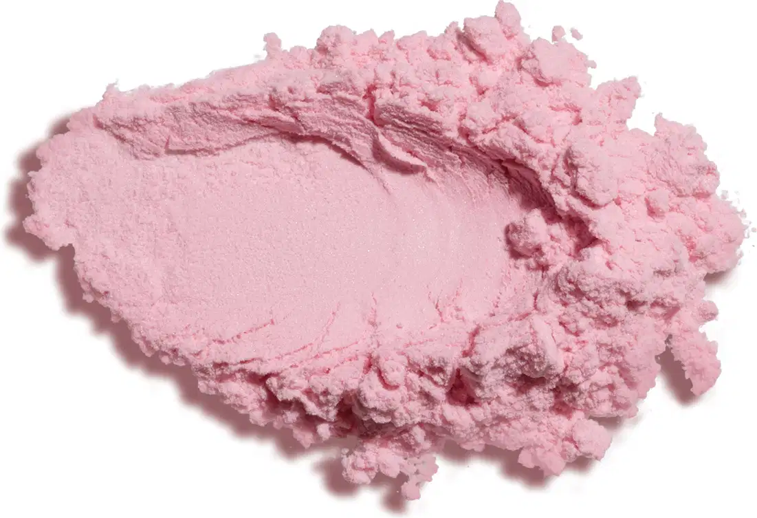Textura de pó compacto fino de cor rosa, com aspecto seco, espalhada sobre superfície branca.