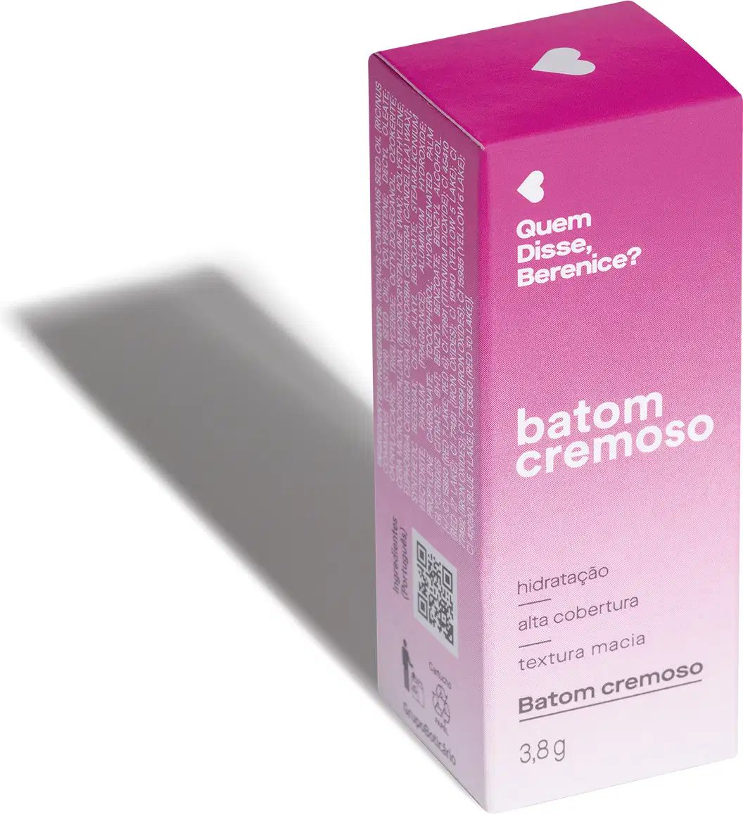 Caixa rosa com coração branco, contendo texto "Quem disse, Berenice?" e "Batom cremoso" em embalagem de 3,8g. A iluminação do ambiente forma uma longa sombra projetada atrás da embalagem.