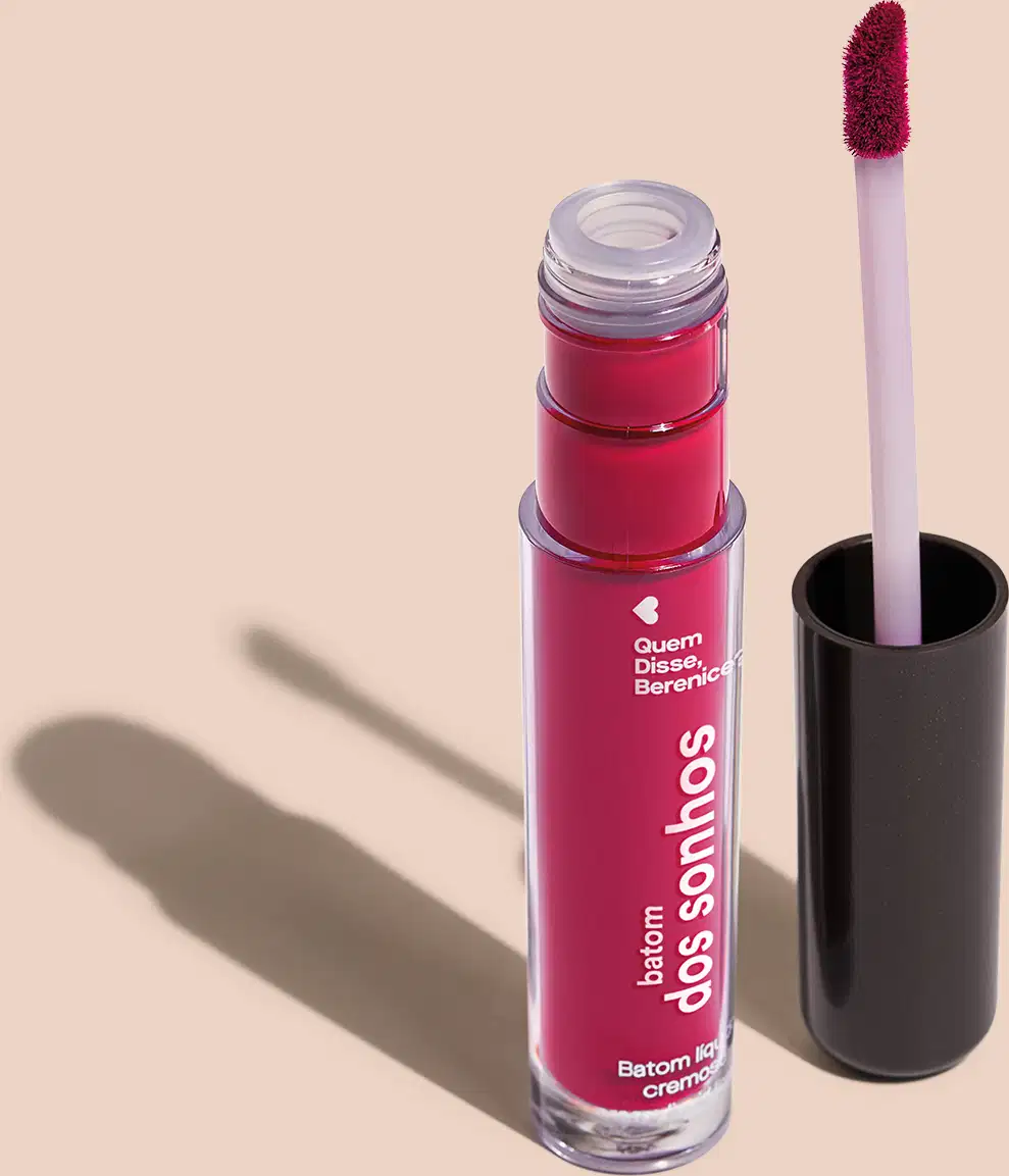 Batom líquido Rosa em frasco transparente de plástico, com aplicador de espuma na cor rosa. O frasco possui uma tampa protetora preta para guardar o aplicador. O rótulo no frasco exibe o nome da marca e do produto em letras brancas sobre fundo rosa.
