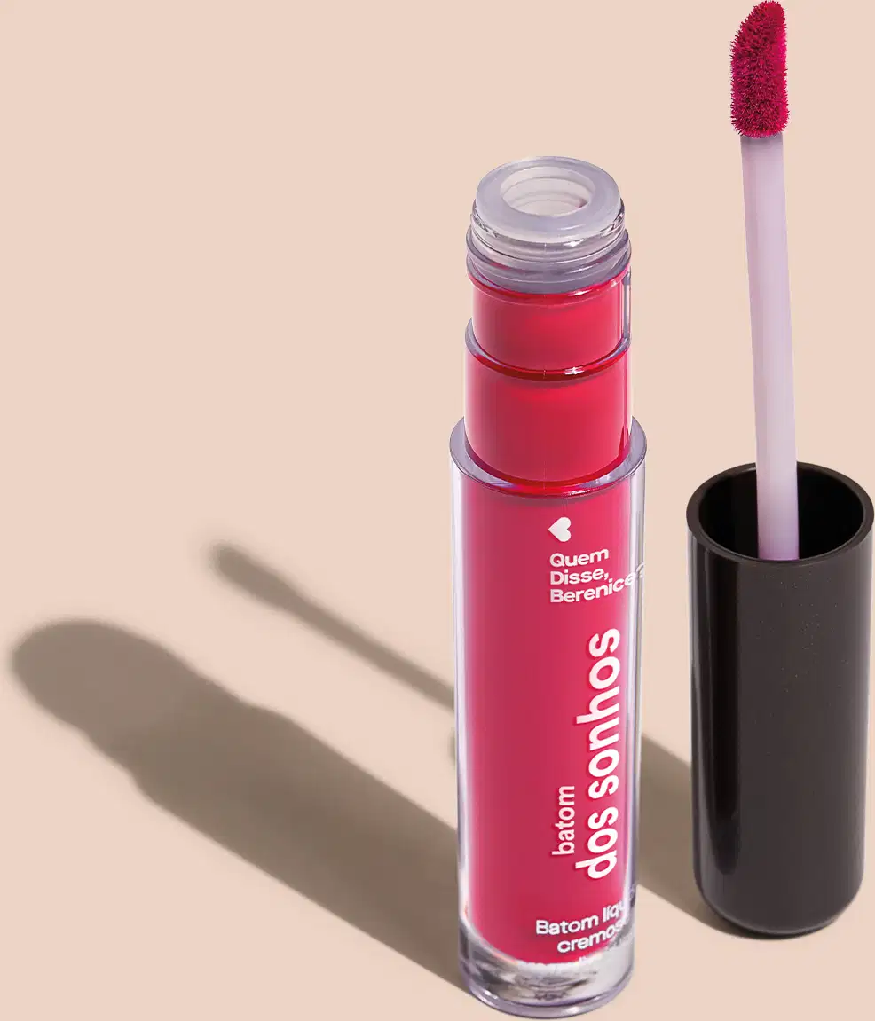 Batom líquido Rosa em frasco transparente de plástico, com aplicador de espuma na cor rosa. O frasco possui uma tampa protetora preta para guardar o aplicador. O rótulo no frasco exibe o nome da marca e do produto em letras brancas sobre fundo rosa.