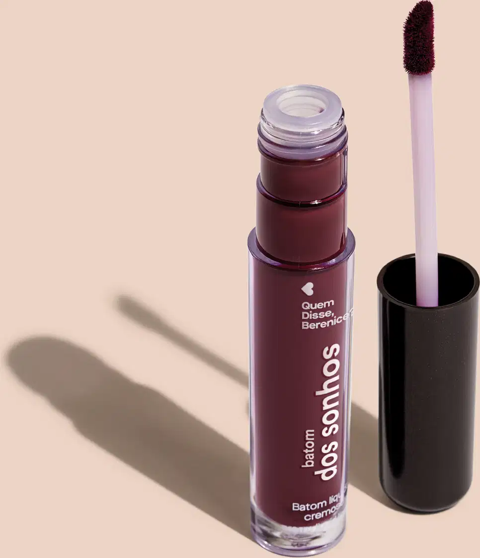 Batom líquido Roxo em frasco transparente de plástico, com aplicador de espuma na cor roxo. O frasco possui uma tampa protetora preta para guardar o aplicador. O rótulo no frasco exibe o nome da marca e do produto em letras brancas sobre fundo roxo.