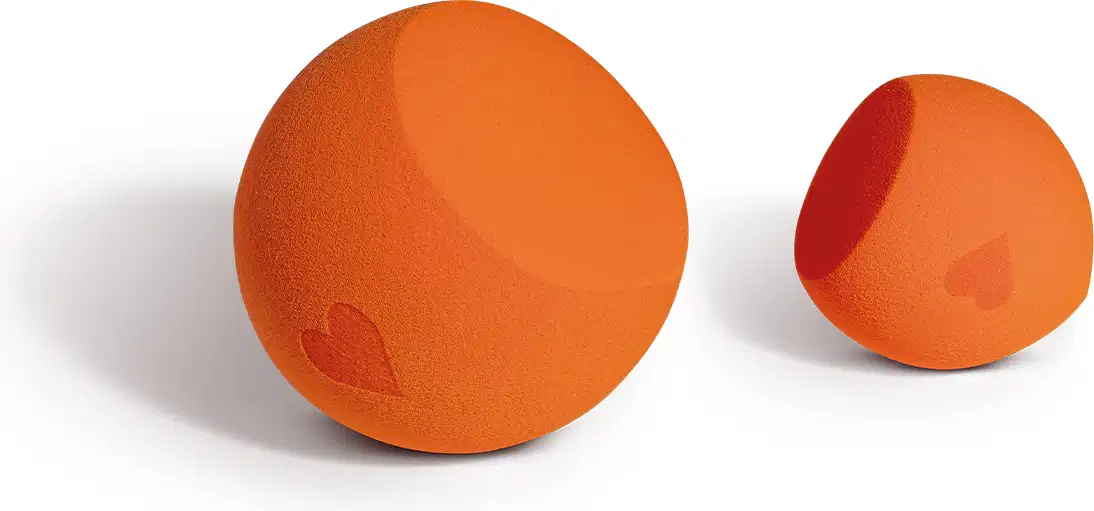 Dois objetos esféricos de cor laranja, com um coração vermelho impresso em um deles. São produtos de beleza da marca Quem Disse, Berenice?