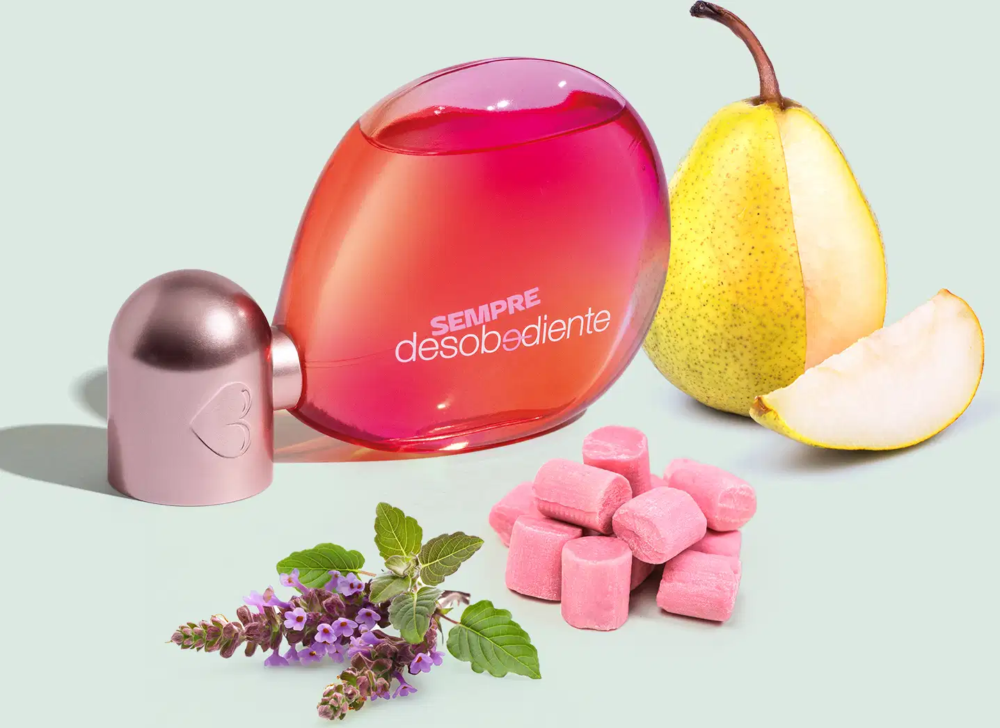 Ao redor do frasco estão dispostos outros elementos, como uma pera amarela, um ramo com flores roxas, um objeto cilíndrico rosa e cubos rosas, possivelmente chicletes. A composição sugere uma fragrância frutada e floral