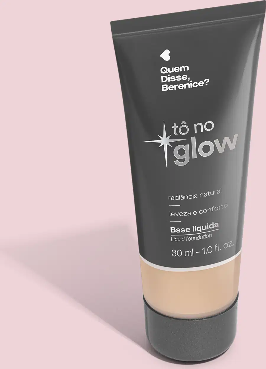 Base líquida em bisnaga preta com base transparente onde é possível ver o tom do produto. Fundo rosa.