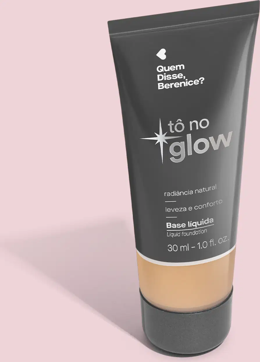 Base líquida em bisnaga preta com base transparente onde é possível ver o tom do produto. Fundo rosa.