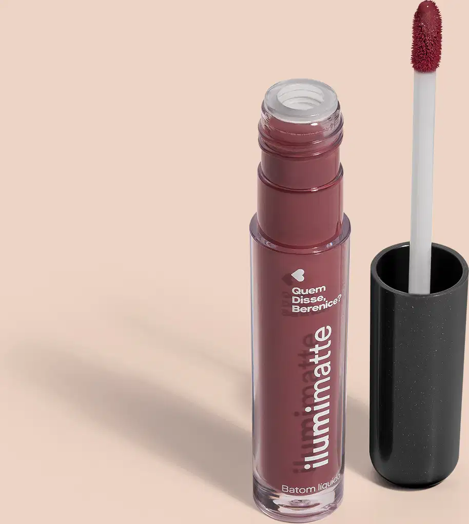 Frasco de batom líquido rosa Roselumi Ilumimatte Quem Disse, Berenice? aberto, mostrando a tonalidade do produto,, com a tampa preta ao lado que traz haste branca e esponja aplicadora na cor rosa em fundo rosado com leve sombreado.