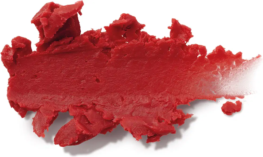 A imagem mostra uma amostra de um pigmento cosmético em pó de cor vermelha. O produto tem uma textura irregular e granulada. Não há embalagens, rótulos ou outros elementos visíveis.