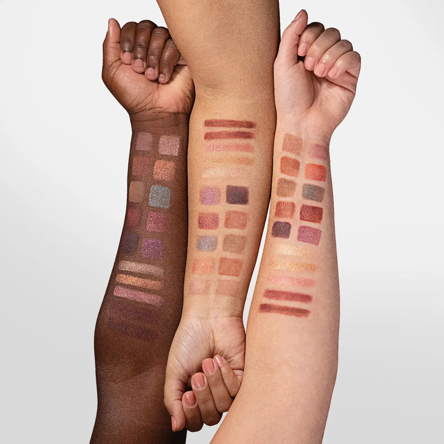 Três braços femininos de cores de peles diferentes e, em cada um deles, amostra das cores da paleta multifuncional Dose De Cor Quem Disse, Berenice? evidenciando a tonalidade delas em cada cor de pele.