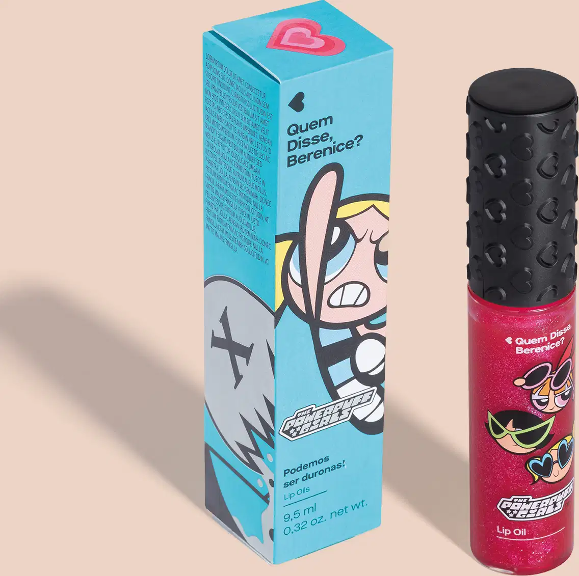 Embalagem azul com ilustração de personagem das Meninas Superpoderosas, contendo um lip oil rosa em embalagem transparente e tampa preta em ambiente liso e claro.