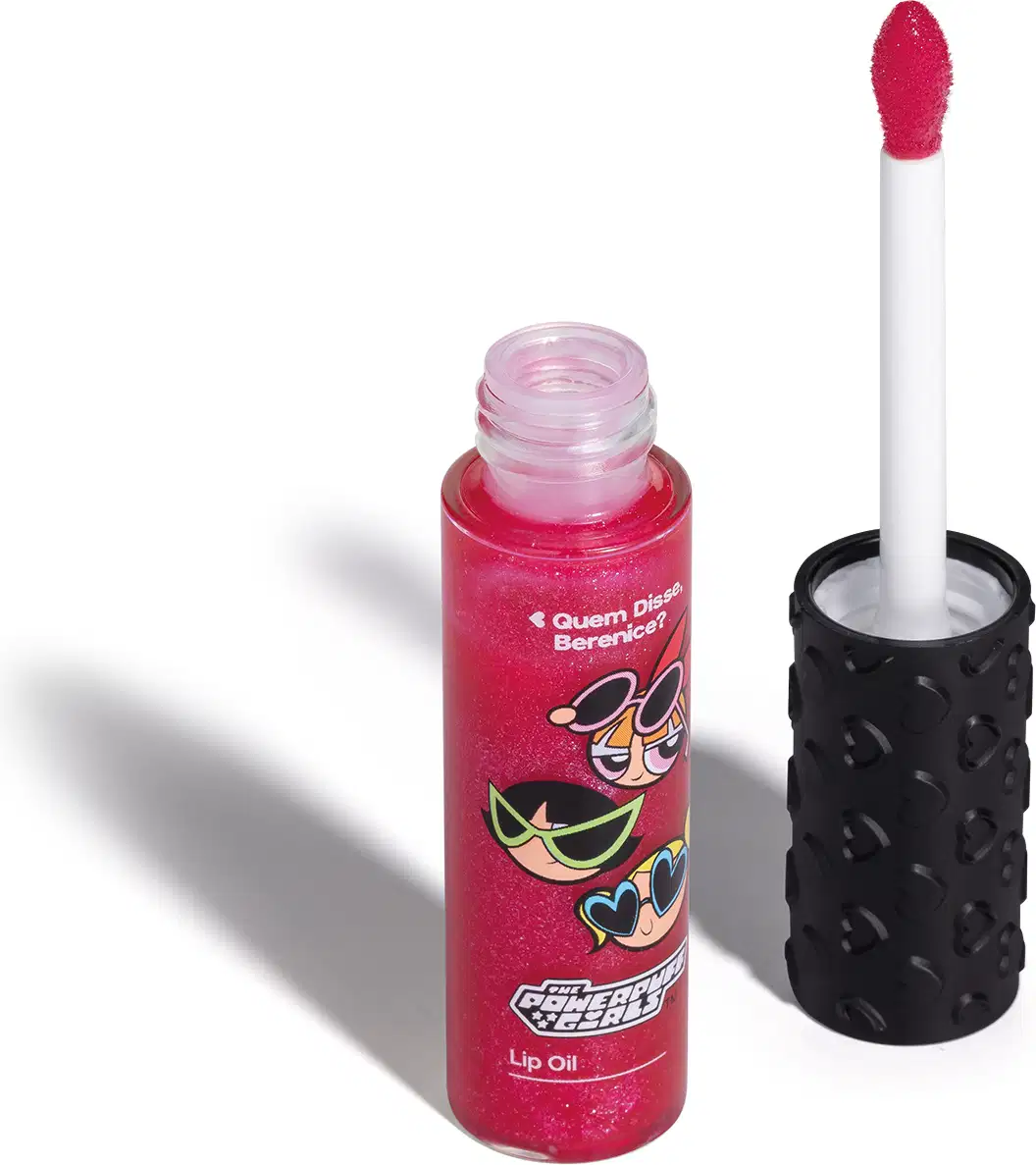 Frasco de lip oil na cor rosa da marca Meninas Superpoderosas Quem Disse, Berenice? em embalagem transparente mostrando a tonalidade do produto, tampa preta com haste e esponjinha vermelha, mostrando ilustração de personagens.