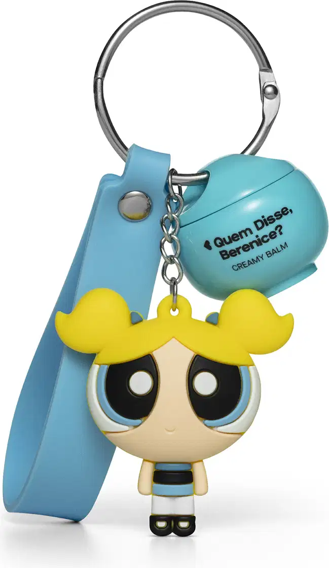 Chaveiro em formato da personagem Florzinha das Meninas Superpoderosas, com vestido azul e cabelo amarelo, preso a um produto da marca Quem Disse, Berenice?.