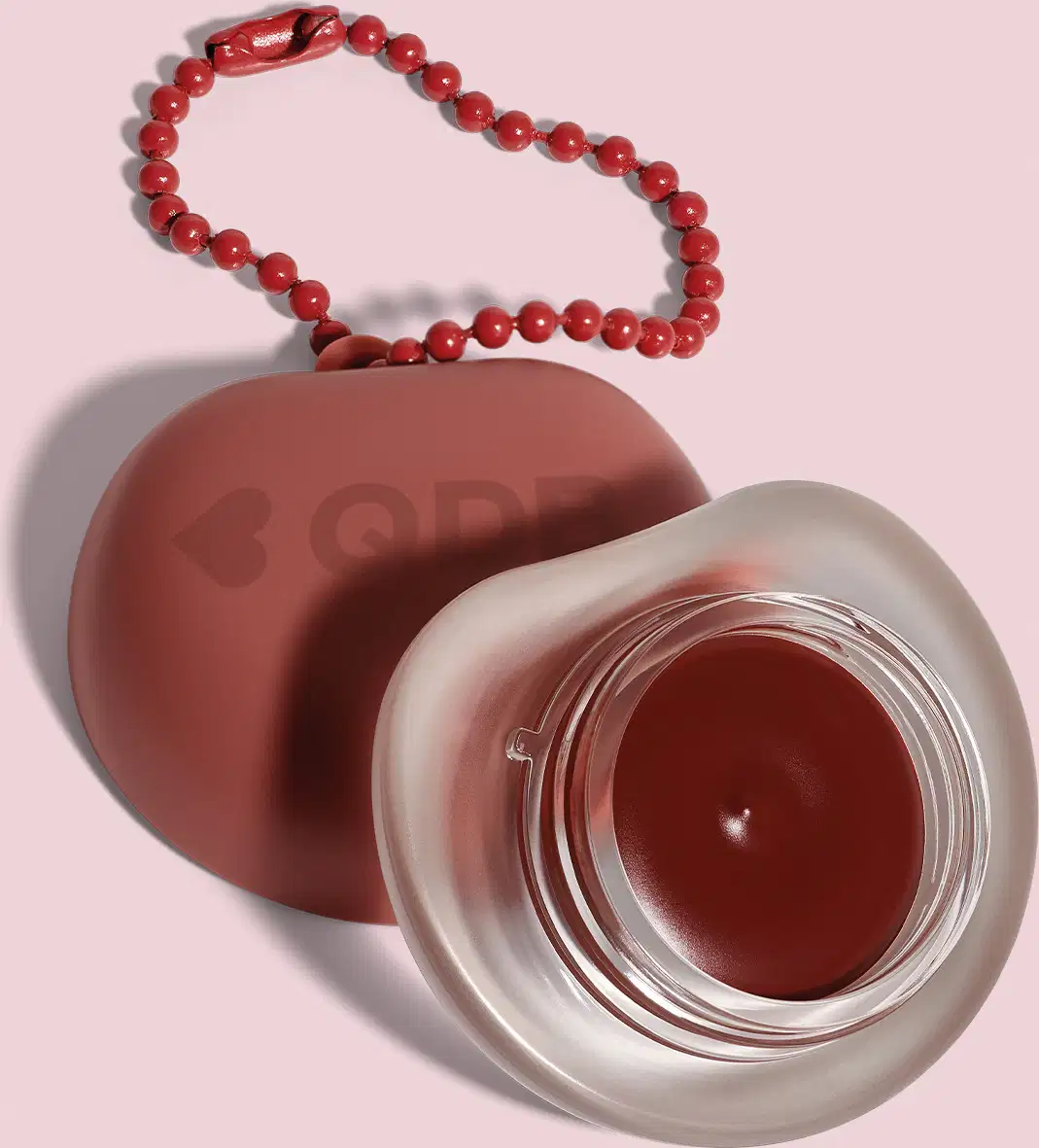 Recipiente marrom com logotipo em forma de coração, O recipiente está sobre um fundo rosa. A imagem sugere um ambiente relacionado a produtos de beleza e cuidados pessoais.
