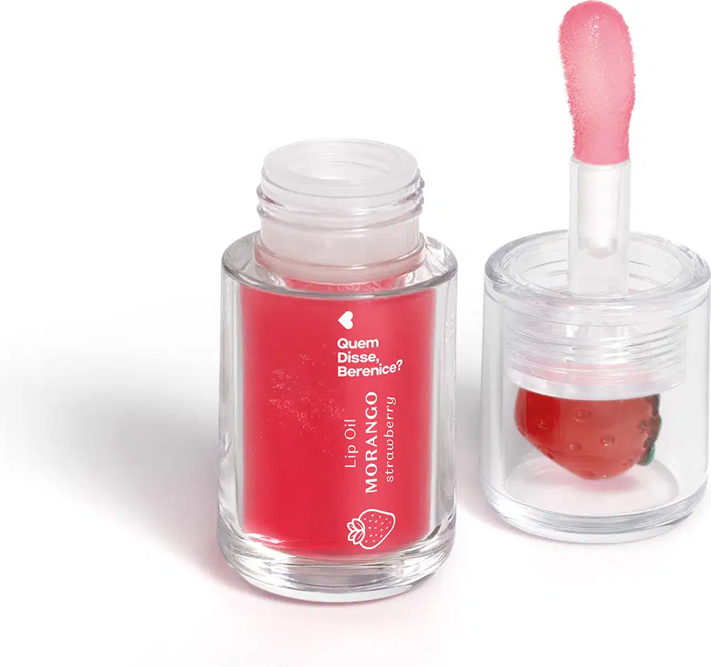 Imagem de um frasco transparente com tampa contendo um líquido vermelho e um aplicador em formato de esponja. Rótulo mostra se tratar do Lip Oil Cuide-se Bem Morango da marca Quem Disse, Berenice. O fundo é branco e há um sombreado.