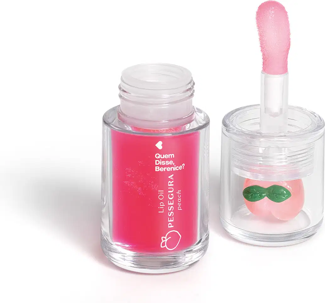 Frasco de lip oil com aplicador em forma de coração e recipiente com brilho labial em formato de pêssego, ambos em embalagens de vidro transparente com rótulos em rosa e verde.