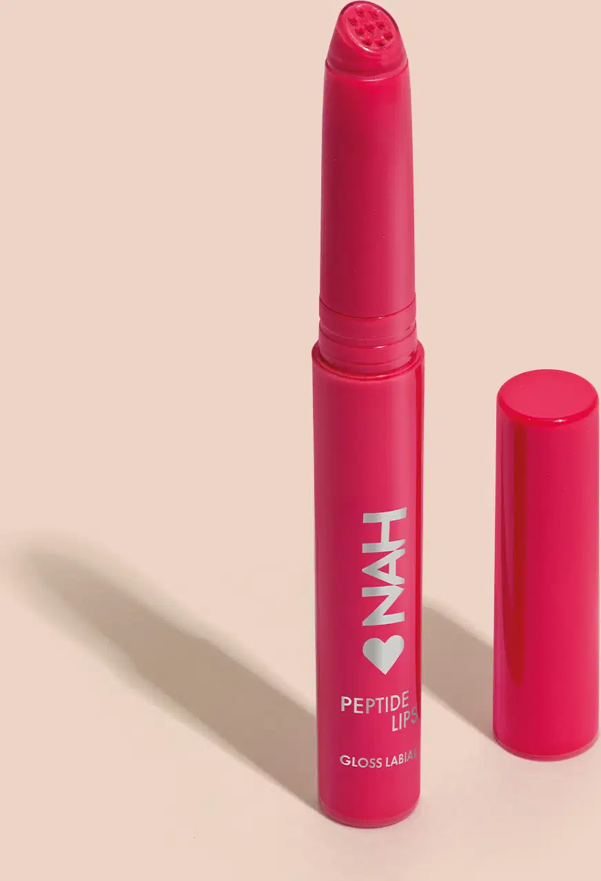 Produto de beleza em embalagem rosa, com rótulo "NAH Peptide Lip Gloss Labial". Apresenta formato de batom com tampa, em cor rosa vibrante.