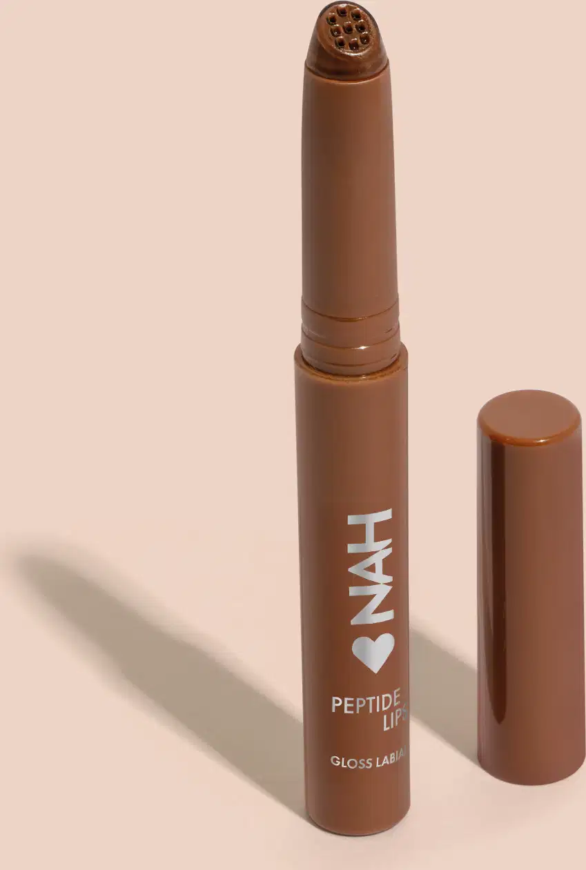 Produto de beleza em formato de batom, com embalagem marrom e rótulo com a marca "INAH" e a descrição "Peptide Lip Gloss". O produto possui uma ponta arredondada e um corpo cilíndrico, sugerindo tratar-se de um batom ou gloss labial.