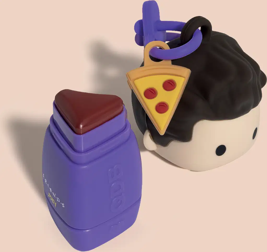 Um batom com tampa:um frasco roxo com tampa e um boneco, com uma fatia de pizza ao lado. 