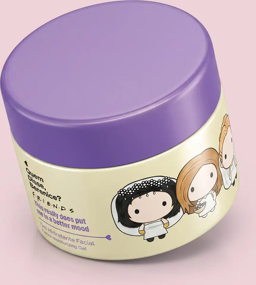 Recipiente de item de perfumaria em forma oval com tampa roxa. Embalagem de cor creme com ilustrações de personagens. Rótulo indica nome da marca "Friends" e menciona "Gel Hidratante Facial". Produto destinado a cuidados com a pele.