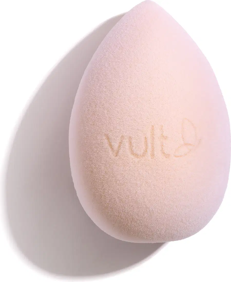 Esponja de maquiagem em formato de gota, com superfície suave e textura aveludada, exibindo o logotipo da marca Vult em sua superfície.