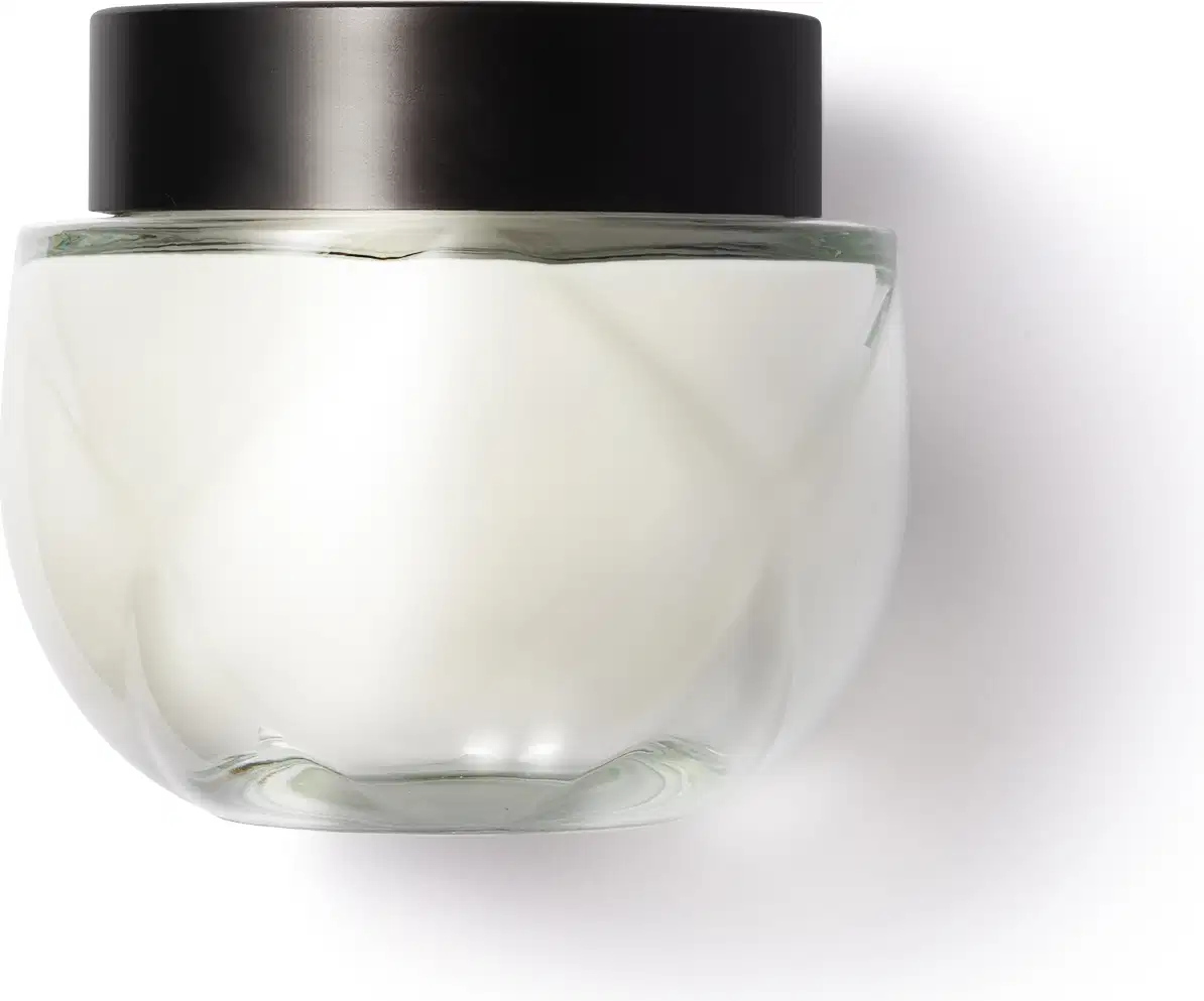 Frasco de vidro arredondado, transparente com tampa preta de rosquear, contendo o creme na cor branca. Design minimalista e elegante.