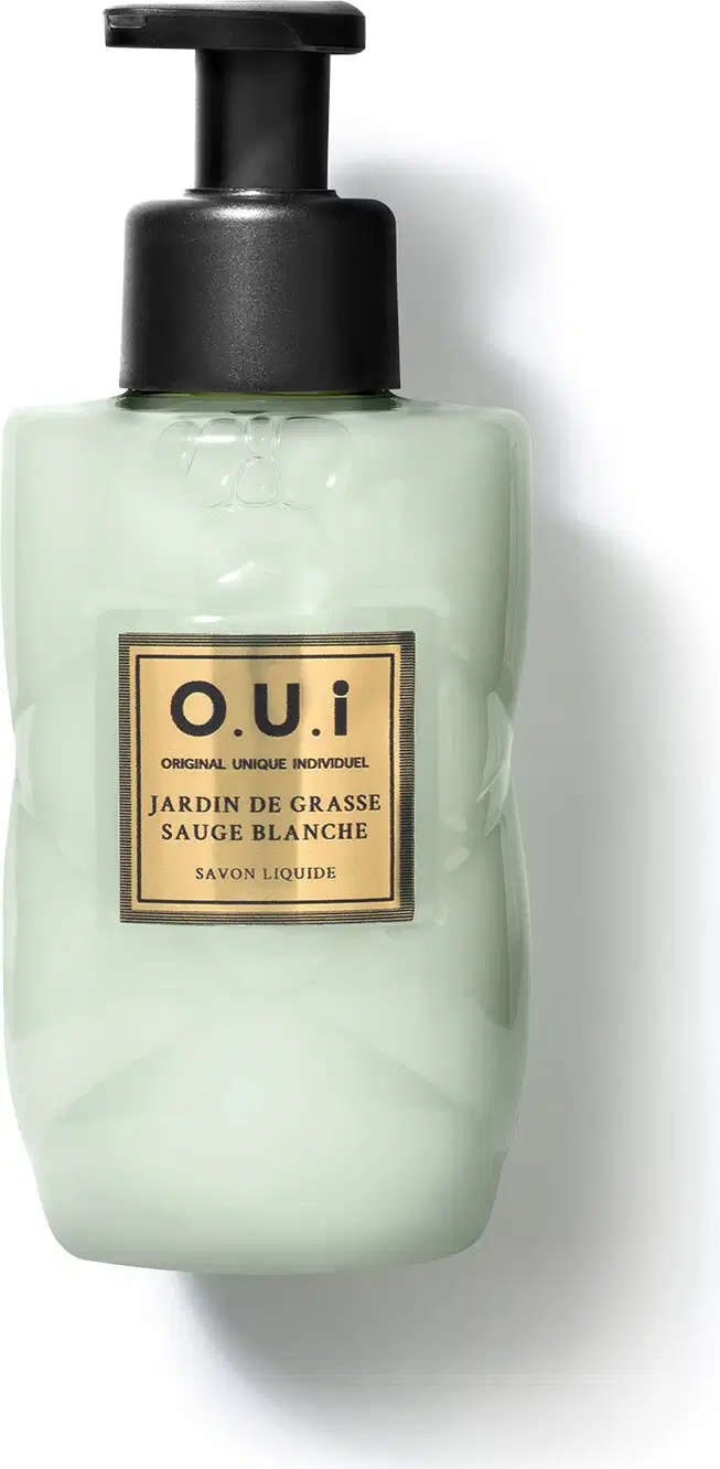 Frasco tipo pump de sabonete líquido da marca O.U.i. com rótulo em fundo verde-claro e detalhes dourados, contendo a descrição "Jardin de Grasse Sauge Blanche" (Jardim de Grama Branca).