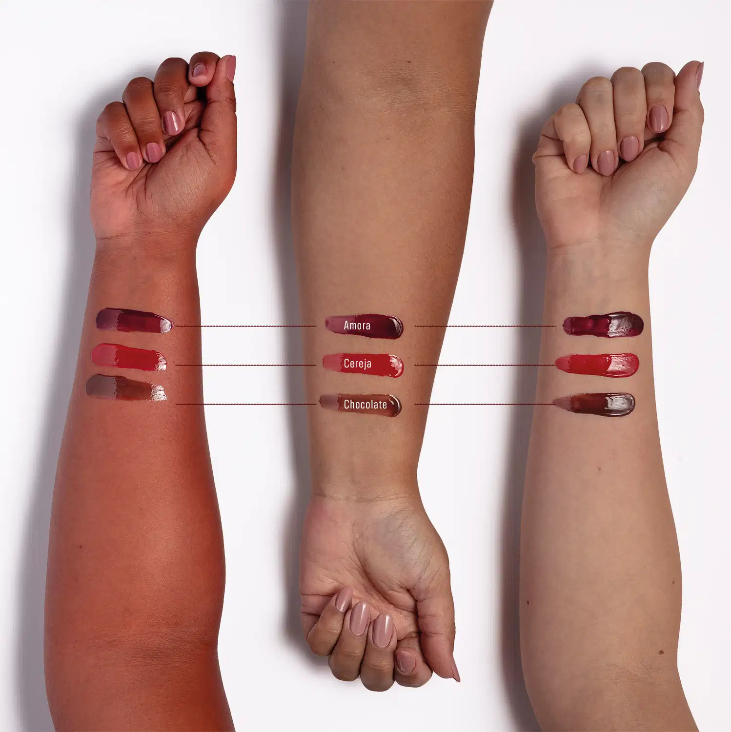 Imagem de braços com aplicação do Hidratante Labial, nas cores Amora em diferentes tons de pele. Em pele avermelhada os tons ficam brilhantes e com menor contraste; em pele parda, ficam com brilho médio, na pele branca, ficam nítidos e vibrantes.