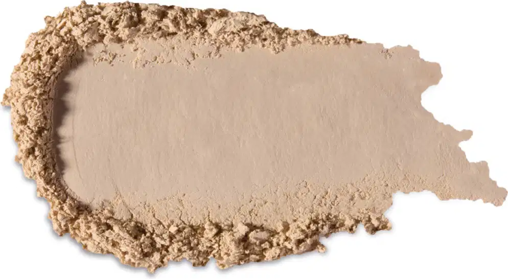 Textura bege clara de produto de maquiagem com acabamento aveludado e superfície irregular, com pequenos grânulos visíveis, indicando a textura em pó.