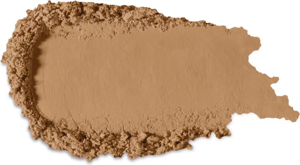 Textura marrom clara de produto de maquiagem com acabamento aveludado e superfície irregular, com pequenos grânulos visíveis, indicando a textura em pó.
