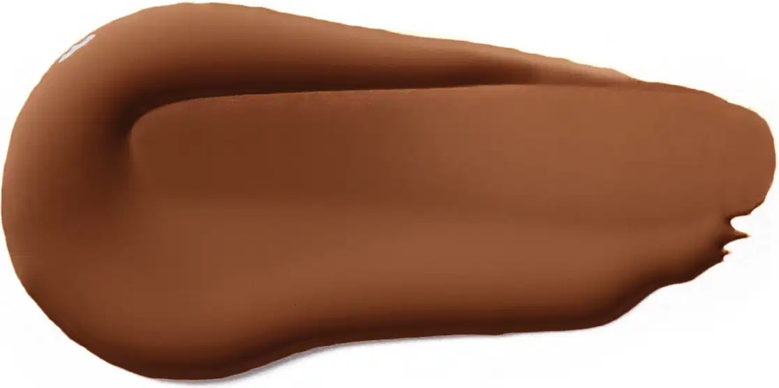 Textura cremosa e opaca em tom de pele escuro, com aparência suave e uniforme, típica de um produto de base ou corretivo da marca Vult.