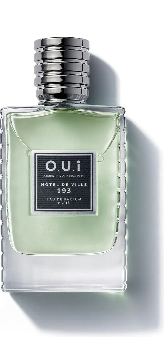 Frasco de item de perfumaria da marca O.U.i, com formato retangular, tampa prateada e rótulo preto com texto "HOTEL DE VILLE 193" em fundo verde claro.