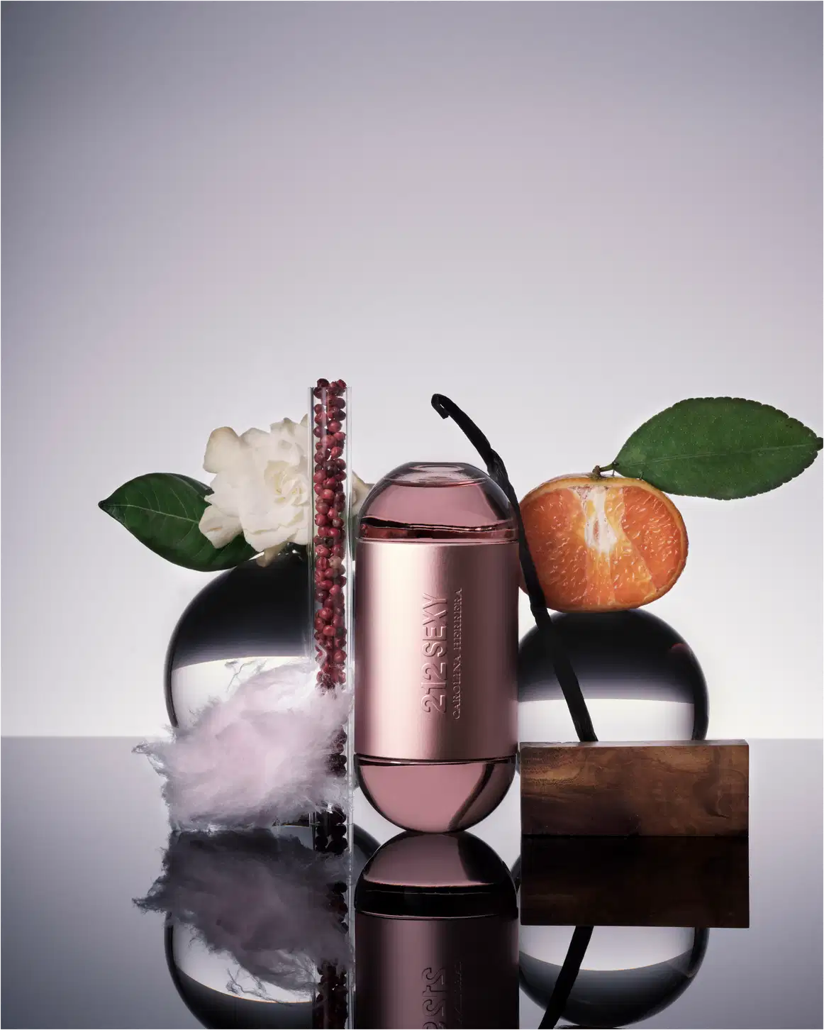 Frasco de perfume Carolina Herrera 212 Sexy, com formato cilíndrico e tampa arredondada, em tons de rosa claro. O rótulo exibe o nome da fragrância em letras prateadas.