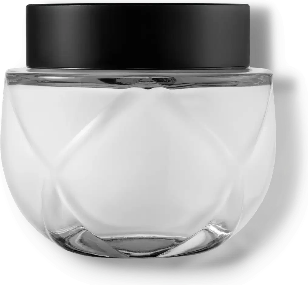 Frasco de vidro transparente arredondado com tampa preta. O recipiente tem uma forma esférica achatada. A tampa preta opaca contrasta com o vidro transparente do frasco que contém o creme na cor branca.