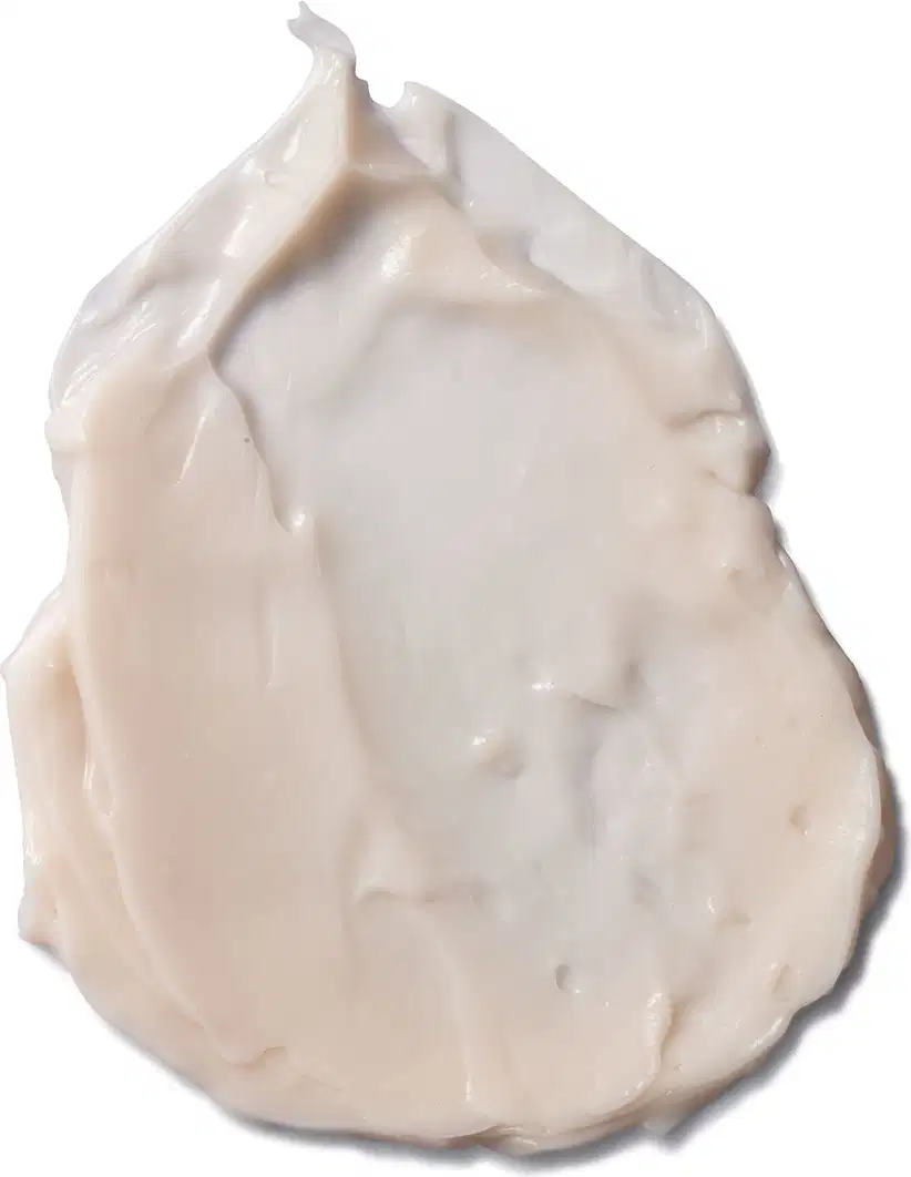 Creme corporal em formato de porção cremosa e texturizada, com coloração branca. A porção apresenta uma forma irregular e pontiaguda no topo. A superfície é lisa e brilhante, sugerindo uma consistência. Não há rótulos ou texto.