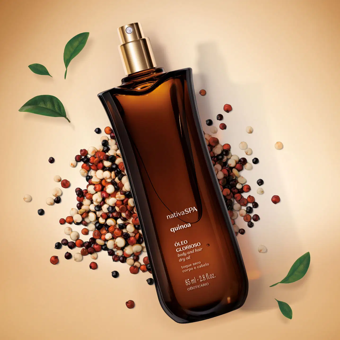 Vidro marrom com pulverizador dourado e letras brancas contendo óleo multifuncional glorioso corpo e cabelos da marca Nativa SPA Quinoa sobre fundo bege, cercado por contas coloridas em tons de vermelho, branco e preto, e folhas verdes decorativas.