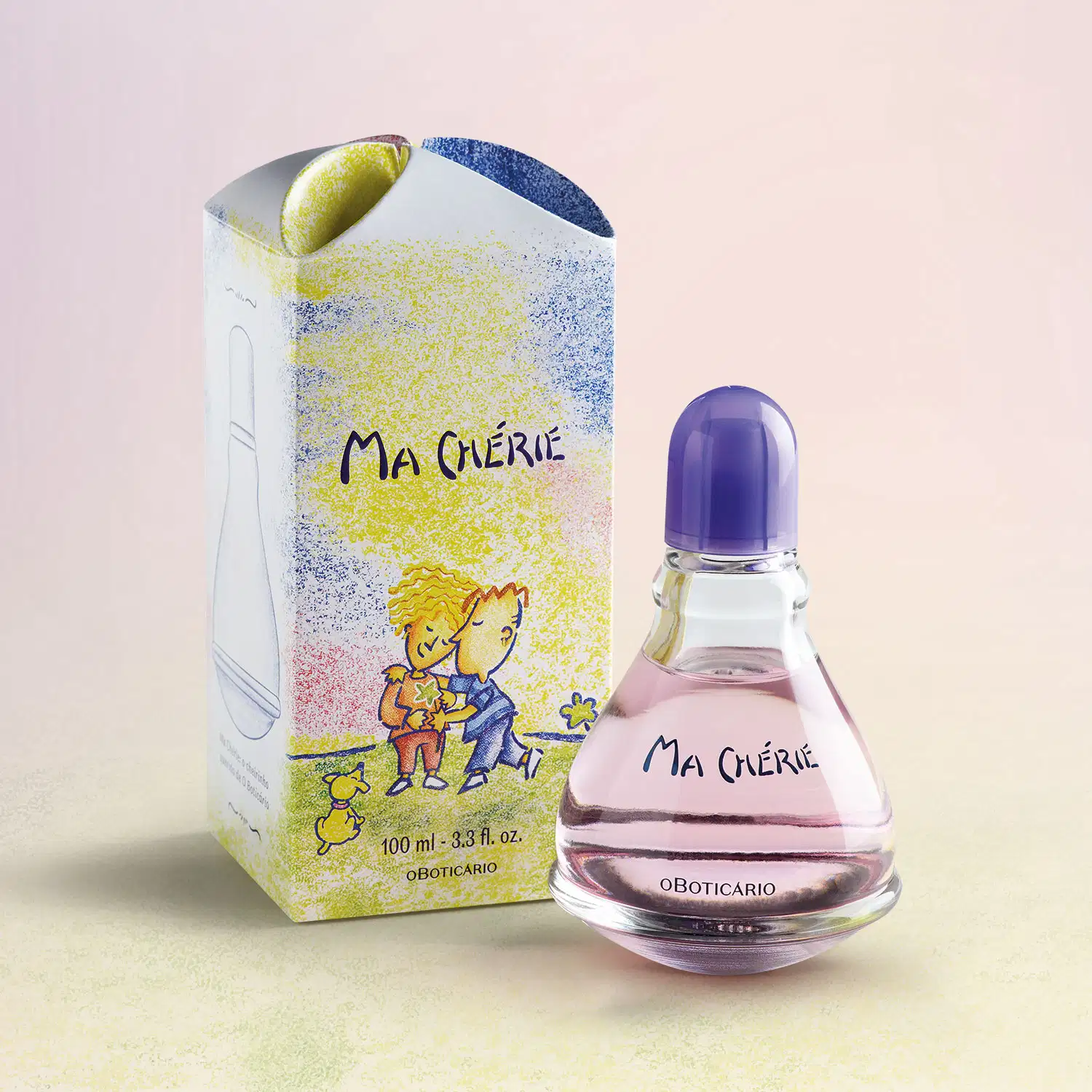 Vidro transparente com fundo arredondado, líquido rosa, tampa e letras azuis, contendo 100ml de desodorante colônia Ma Chérie, ao lado de embalagem colorida com ilustração infantil, sobre superfície bege claro com pera amarela ao fundo.