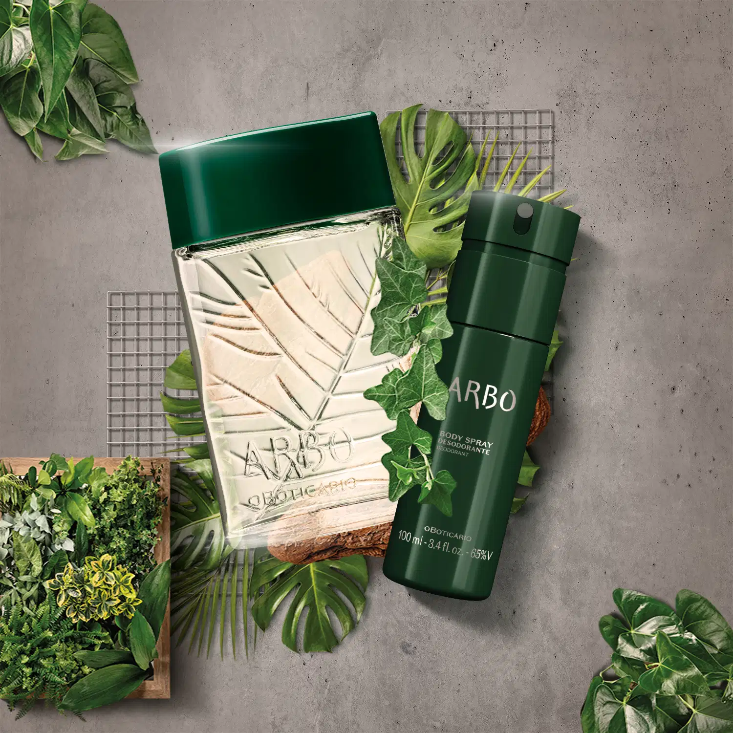 Dois itens Arbo: vidro transparente com folhas em relevo, liquido esverdeado e tampa verde de desodorante colônia e frasco verde descuro com letras pratas de body spray, sobre superfície cinza com plantas verdes, grades metálicas e madeira ao redor.