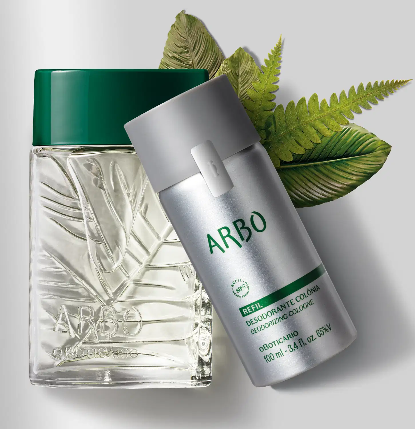 Duas embalagens contendo desodorante colônia Arbo, sendo um vidro transparente verde com folhagens em relevo e tampa verde escuro e refil em frasco prateado com tampa e letras cinzas cercados por folhas verdes e fundo cinzento claro.