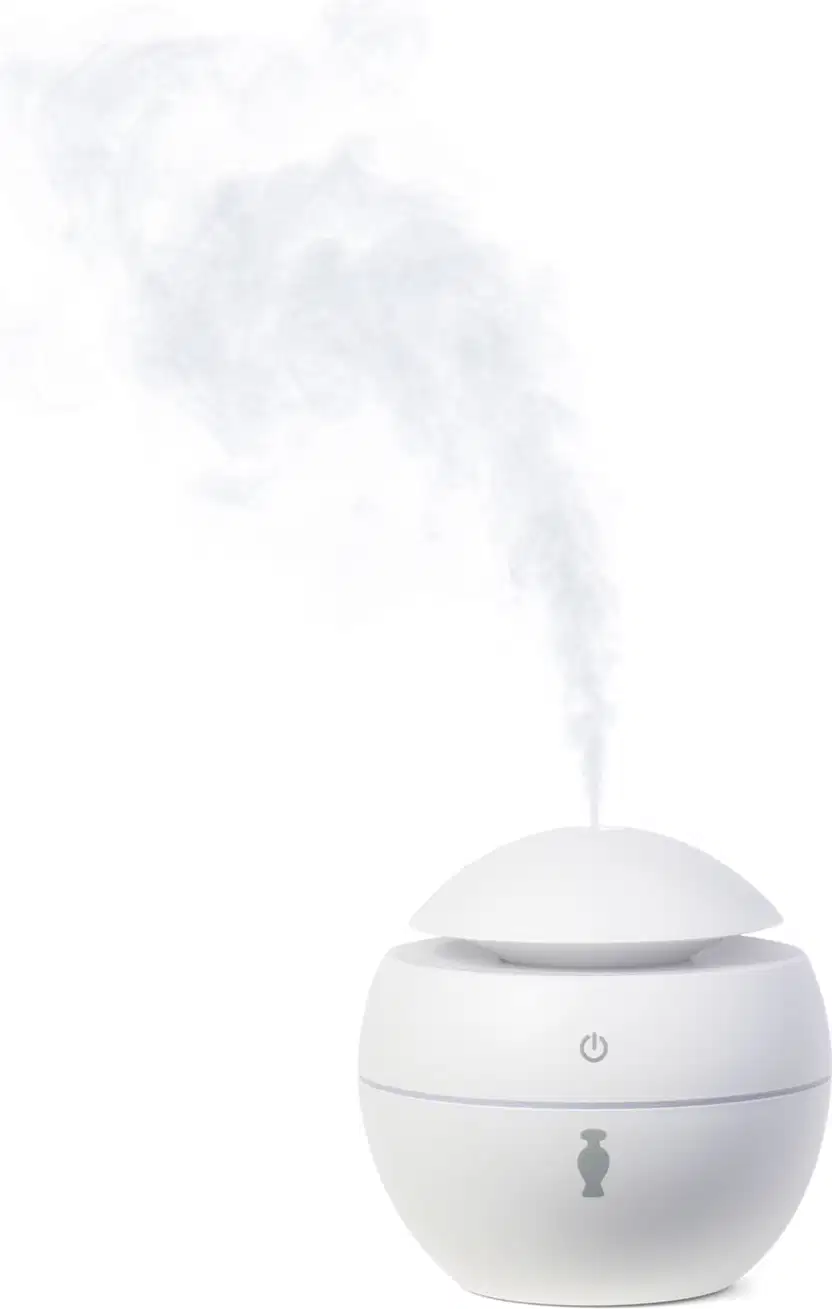 Aromatizador elétrico de ambientes branco com tampa em formato de cúpula, botão power cinza no topo e ícone da marca O Boticário no corpo do pote. Há fumaça branca saindo do topo do aparelho.