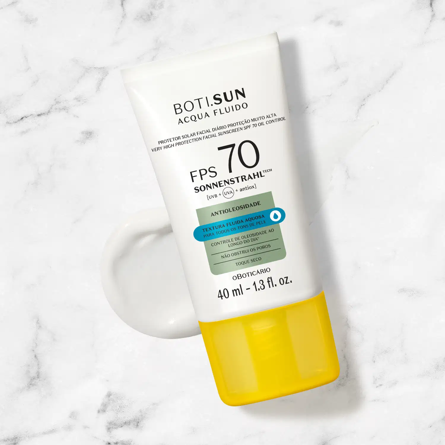 Frasco branco com tampa amarela, letras pretas e detalhes prata e azul, de protetor solar facial antioleosidade FPS 70 Acqua Fluído da marca Boti.Sun posicionado sobre superfície de mármore cinza e branco com sombra projetada ao lado.