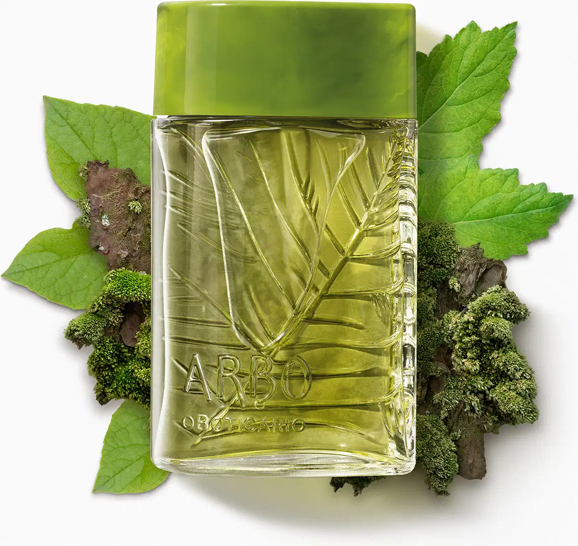 Vidro quadrado transparente com folhas em relevo, líquido verde e tampa verde musgo contendo 100ml de desodorante colônia Arbo Forest cercado por folhas verdes e musgo em superfície branca.