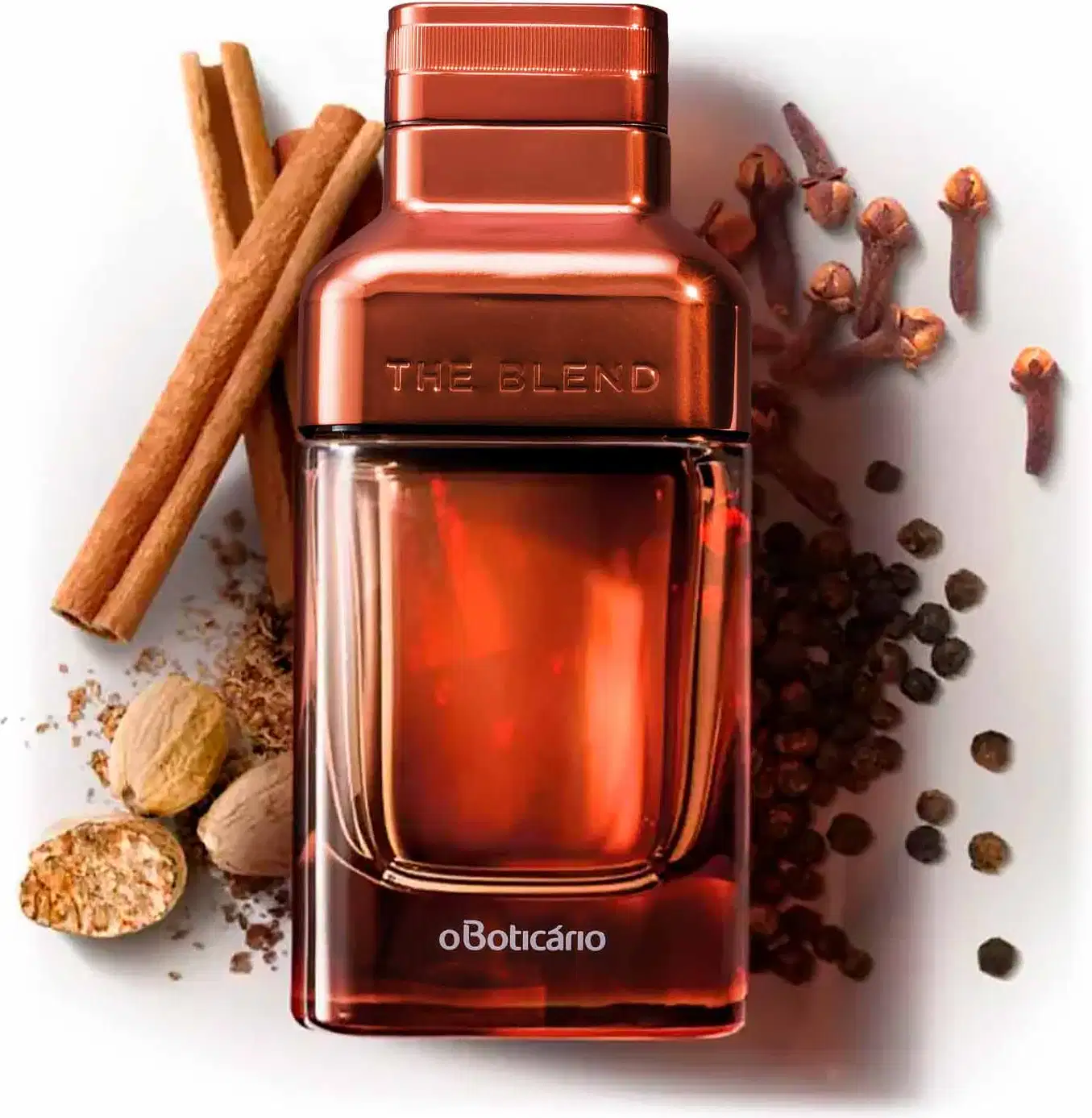 Vidro em tom de marrom fosco com detalhes em marrom metalizado e letras azuis contendo Eau de Parfum The Blend cercado por canela em pau, noz-moscada, cravo-da-índia e sementes de pimenta sobre superfície branca.